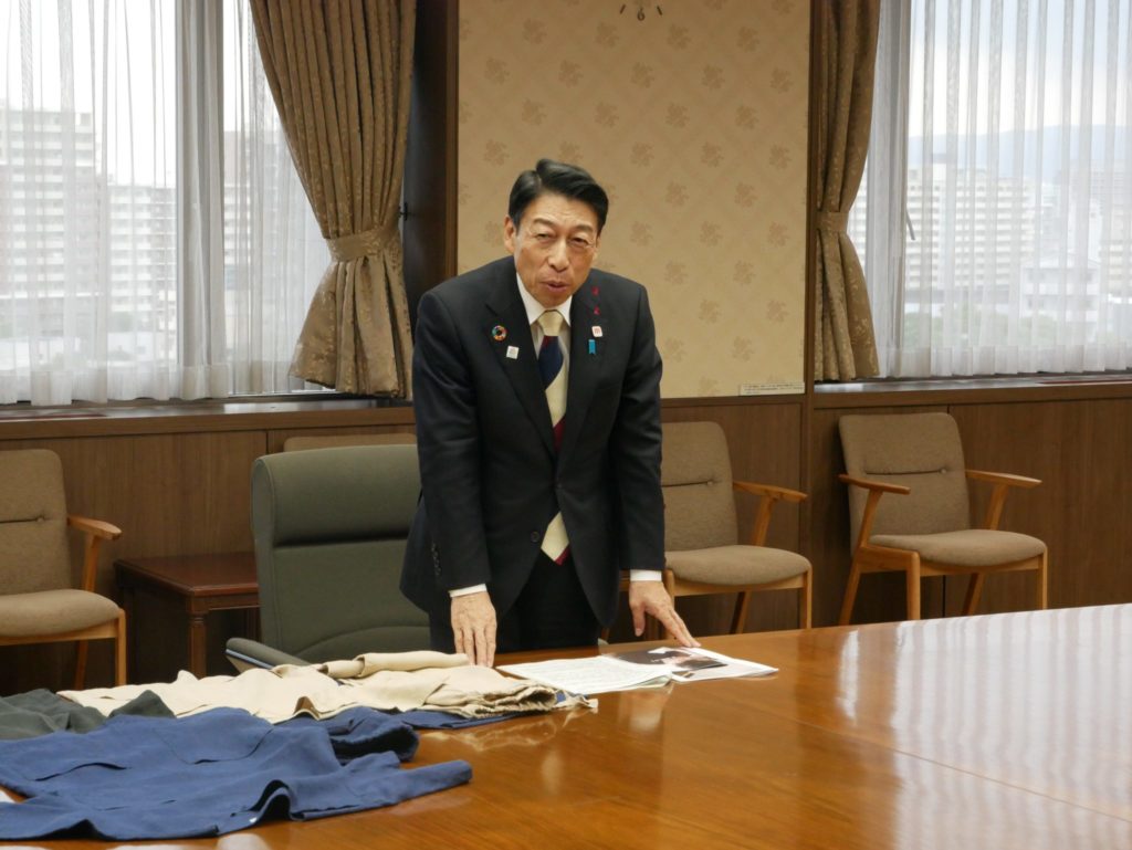 Governor Seitaro Hattori of Fukuoka Prefecture giving remarks on Working Hasegawa's initiatives, with sukui samples on the desk.